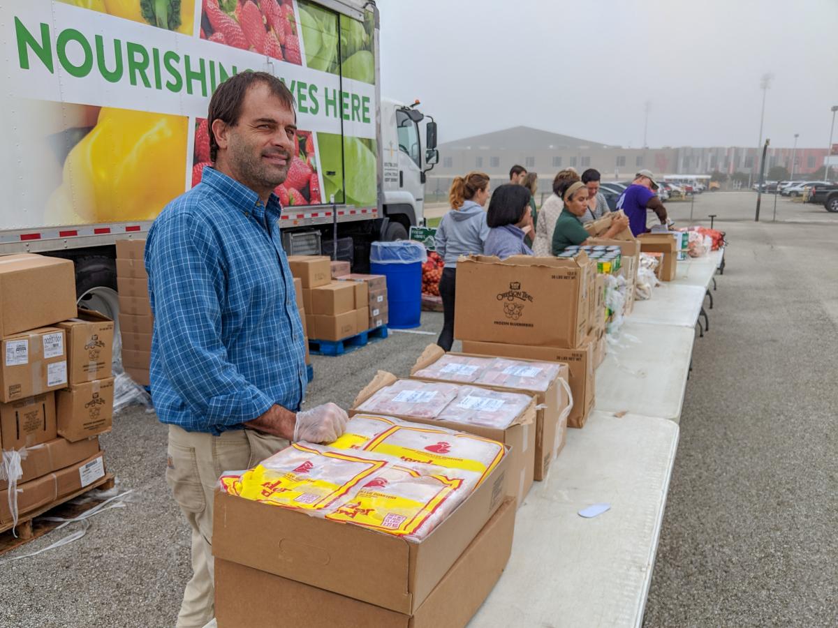 Food Policy Manager Edwin Marty stands at a distribution table ready to pass out frozen meat. 