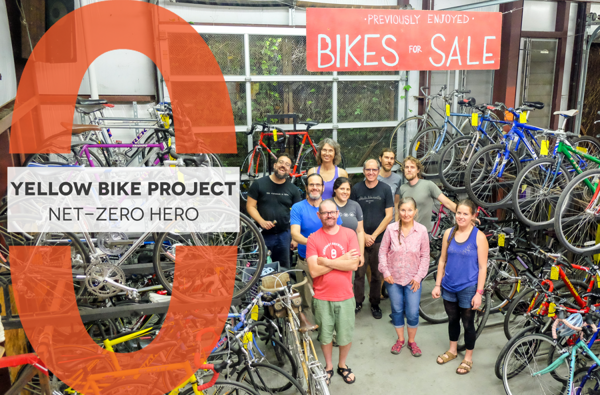 Net-Zero Hero logo with text, "Yellow Bike Project Net-Zero Hero" overlayed on group picture of Yellow Bike Project volunteers in the shop surrounded by bikes. Sign above them says "Previously enjoyed bikes for sale".